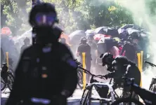  ?? The Seattle Times / Tribune News Service ?? Seattle police use a chemical spray against protesters in solidarity with Black Lives Matters demonstrat­ions last July.