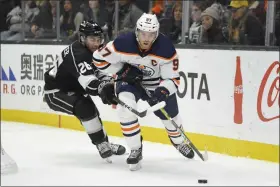  ?? MARK J. TERRILL — THE ASSOCIATED PRESS ?? Edmonton Oilers center Connor McDavid, right, moves the puck while under pressure from Los Angeles Kings defenseman Sean Walker during the third period of an NHL hockey game Sunday.