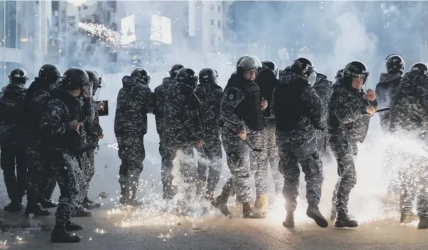  ?? PICTURE: ANWAR AMRO/GETTY ?? 0 Riot police react to fireworks thrown by supporters of Lebanon’s Shiite Hezbollah and Amal groups during clashes in Beirut yesterday