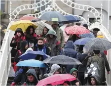  ?? Photo: Damien Eagers ?? Pedestrian­s on Dublin’s Ha’penny Bridge are caught in yet another April shower.