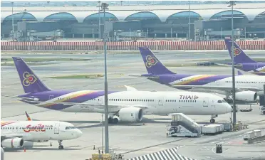  ?? SOMCHAI POOMLARD ?? THAI aeroplanes parked at Suvarnabhu­mi airport. With tourism at a standstill, operators are anxious for aid.