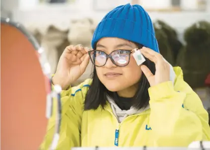  ?? KYLE TELECHAN/POST-TRIBUNE ?? Hammond resident Rachel Torralva, 18, tries on glasses as she and her mother shop for Black Friday deals at the JCPenney at Southlake Mall. Crowds were comparable to recent years, as the retailer has run deals earlier, said JCPenney store manager Jodi Ringler.