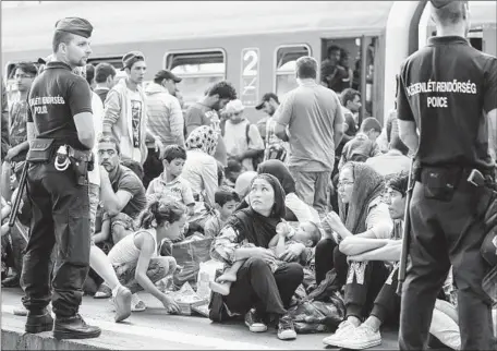  ?? Matt Cardy
Getty Images ?? POLICE STAND GUARD as migrants sit on the platform of reopened Keleti station in central Budapest, Hungary. Some migrants became defiant after rail service to Austria and Germany was canceled, boarding trains and ignoring orders to get off.