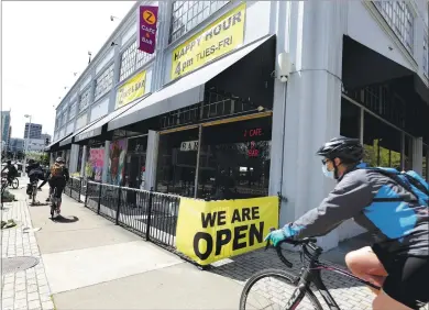  ?? RAY CHAVEZ — STAFF PHOTOGRAPH­ER ?? Bike riders pAss A lArge “We Are Open” sign displAyed At Z CAfe & BAr on BroAdwAy in OAklAnd on April 3.