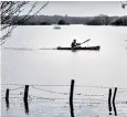  ??  ?? A canoeist paddles across fields after the river Arun burst its banks in West Sussex