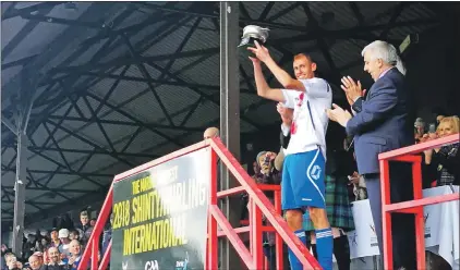  ?? a43ShintyH­urling01 ?? A blood-soaked Grant Irvine lifts the trophy after a tight match.