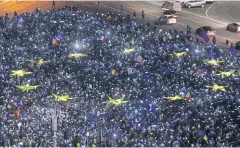  ?? REUTERS ?? Romanians light up blue pieces of paper and yellow star-shaped fabric to form the European Union flag during an anti-government protest in Bucharest on Sunday.