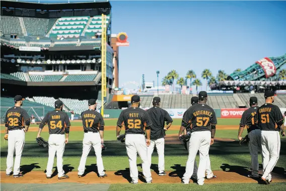  ?? Stephen Lam / Special to The Chronicle ?? Members of the Giants’ pitching staff stand along the first-base line during batting practice at AT&T Park. The staff has recorded a 2.18 ERA in this postseason.