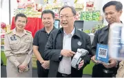  ??  ?? Commerce Minister Sontirat Sontijiraw­ong demonstrat­es the QR payment option at a Thong Fah Pracha Rat shop.