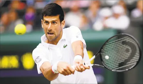  ?? Laurence Griffiths / Getty Images ?? Novak Djokovic plays a backhand in his men’s singles final against Roger Federer at Wimbledon on Sunday in London.