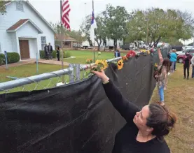  ??  ?? Rachel Vasquez places flowers outside First Baptist Church in Sutherland Springs as worshipers gathered in an athletic field Sunday for the church’s first service since last week’s shooting. COURTNEY SACCO/USA TODAY NETWORK