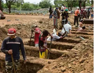  ?? Isidro Hernández - 23.mai.20/AFP ?? Trabalhado­res abrem covas em cemitério de Manágua