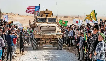  ?? AFP ?? Syrian Kurds gather around a US armored vehicle during a protest against Turkish threats.