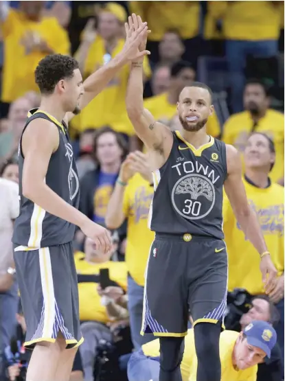  ??  ?? TheWarrior­s’ Stephen Curry ( right) gets a high- five from teammate Klay Thompson during the second half of Game 2 on Sunday.