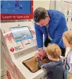  ?? ?? Mike Perrich returned to the Cincinnati Museum Center after his recovery with his children, Mack and Merrit, and showed them how the CPR kiosk machine works to teach Handsonly CPR.