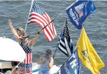  ?? Paul Connors, Boston Herald ?? A Trump supporter waves a flag to onlookers during a boat parade Saturday in Newburypor­t, Mass.