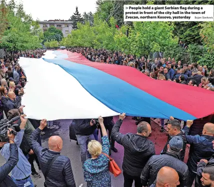  ?? Bojan Slavkovic ?? > People hold a giant Serbian flag during a protest in front of the city hall in the town of Zvecan, northern Kosovo, yesterday