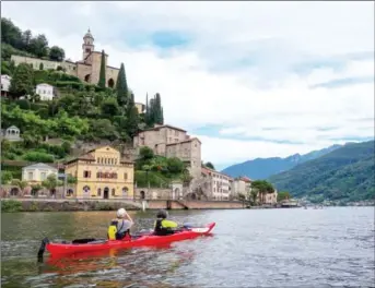  ?? THE WASHINGTON POST DINA MISHEV/ ?? Two Kayakers take photos of the Church of Santa Maria del Sasso, the 15th-century structure standing tall on its precarious hillside perch, as they approach the village of Morcote on Lake Lugano. Leonardo da Vinci visited the Italian lakes frequently...