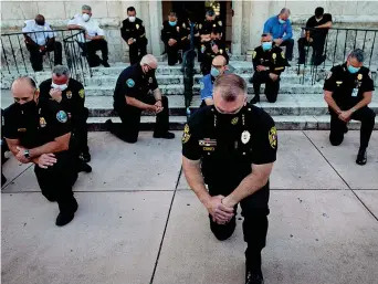  ??  ?? Gli agenti di polizia in ginocchio durante una manifestaz­ione a Coral Gables, in Florida, per la morte di George Floyd