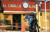  ?? PEDRO PARDO/GETTY-AFP ?? A police officer moves in front of the White Horse Bar on Wednesday in the coastal city of Coatzacoal­cos, Mexico.