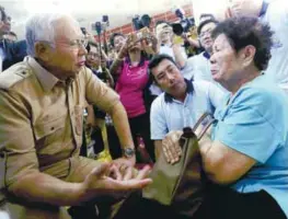  ??  ?? Najib speaking to flood victim Loh Saw Kang, 75, during his visit to a relief centre yesterday.