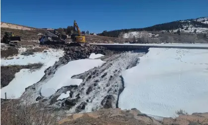  ?? Photograph: Matt Call/AP ?? Crews use heavy machinery to place boulders downstream of the cracked Panguitch Lake dam in Panguitch, Utah, on 10 April.