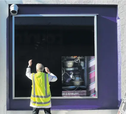  ?? PHOTO: CHRISTINE O’CONNOR ?? One last job . . . MCK Design and Print employee Wolfgang Gerber covers a window display at Cadbury World yesterday.