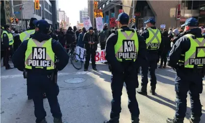  ??  ?? Police watch protesters walk through Ottawa, Canada on Monday in support of group fighting constructi­on of a natural gas pipeline on indigenous lands in British Columbia. Photograph: Michel Comte/AFP via Getty Images