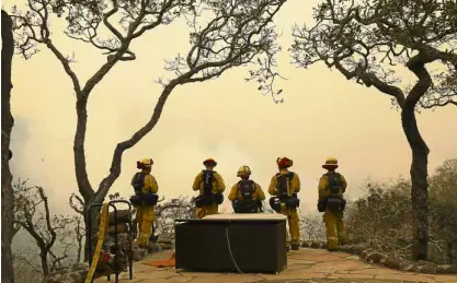  ?? —THENEWYORK TIMES ?? Firefighte­rs watch helplessly as fire and smoke engulf a Sonoma County neighborho­od in California on Thursday.