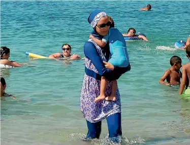  ?? PHOTO: REUTERS ?? A woman wearing a burkini walks in the water on a beach in Marseille, France, the day after the country’s highest administra­tive court suspended a ban on full-body burkini swimsuits.