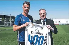  ??  ?? HOMENAJE. Cristiano Ronaldo recibe la camiseta de manos del presidente Florentino Pérez por haber anotado el gol 400.