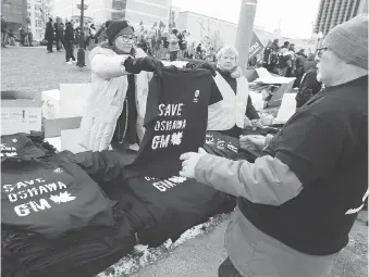  ??  ?? Unifor volunteer Allison Kozolanka sizes up a T-shirt for Carl Dillman at Dieppe Park. The union is promising an all-out campaign that will reach into Wall Street against the planned closure of the GM plant in Oshawa.