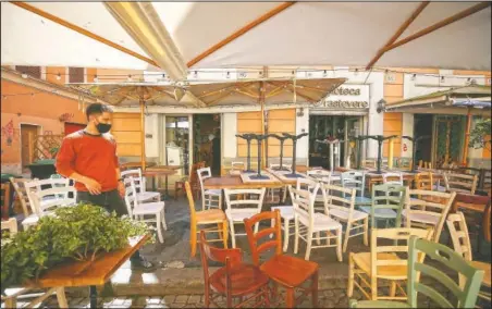  ?? (LaPresse/Cecilia Fabian) ?? Chairs and tables are prepared outside a restaurant in Rome. Even Italy’s tentative opening is satisfying no one. The nation’s weary virologist­s worry the country will see people crowding bars and restaurant­s and bring yet another spike to the virus that hasn’t receded yet.