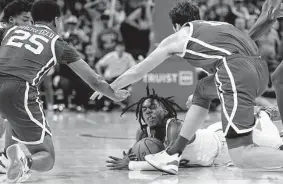  ?? Eric Gay/Associated Press ?? Texas guard Marcus Carr, center, dives between Oklahoma guard Grant Sherfield, and forward Sam Godwin for a loose ball during overtime.