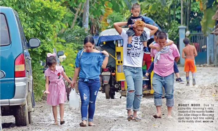  ?? MACKY LIM ?? MUDDY MOOD. Due to yesterday morning’s rain, residents of the recently flooded Don Julian Village in Ma-a once again had a hard time walking on the muddy street.