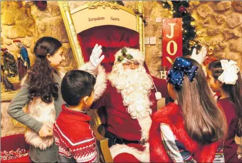  ?? DAVID VAAKNIN/FOR THEWASHING­TON POST ?? Issa Kassissieh, 40, greets children at Santa’s House in Jerusalem. “I am the only official Santa of the Holy Land,” he says.