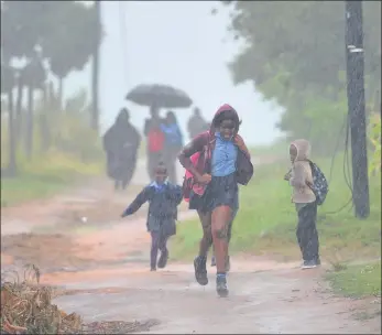  ?? PICTURES: ITUMELENG ENGLISH ?? Schoolchil­dren in Tshabalala township brave the elements as they make their way to school on Friday. Heavy rains continued to fall as Dineo, the storm that was downgraded from a tropical cyclone, hit Mpumalanga.