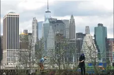  ?? CARLO ALLEGRI / REUTERS ?? People work on a floating barge, which is planted with fruit trees, with the Manhattan skyline in the background.