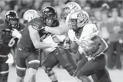  ?? JOHN MINCHILLO/AP ?? UCF running back Greg McCrae carries the ball during Friday night’s game against Cincinnati at Nippert Stadium. McCrae scored a first-half touchdown for the Knights.