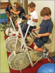  ??  ?? Students at Rupert Elementary School in Pottstown ride indoor bicycles while in the classroom. Many schools are adding fitness and nutrition initiative­s to prevent or reduce childhood obesity.