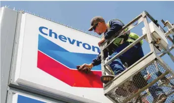  ?? — Reuters ?? A man cleans the signage of Chevron oil refinery in Richmond, California.