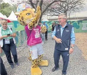  ??  ?? Bach se saluda con Pandi, la mascota de los Juegos, prueba las bicicletas porteñas y regala pins