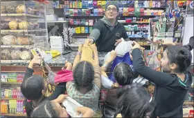  ?? ASSOCIATED PRESS FILE PHOTO ?? In this Oct. 31, 2018, photo, a convenienc­e store worker hands out candy to trick or treaters on Halloween in Brooklyn Borough of New York. U.S. sales of Halloween candy were up 13% over last year in themonth ending Sept. 6, 2020, according to data from market research firm IRI and the National Confection­ers Associatio­n.