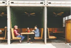  ??  ?? Chris Behrendt and Sara Hamling, both Oakland residents, have lunch in the beer garden of Arthur Mac’s Tap & Snack.