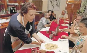  ??  ?? La chef Claudia Vezzali sirve un plato de reginelle al ragú blanco de cerdo pelón durante la cena orgánica