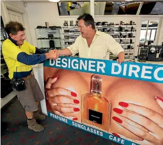  ?? PHOTO: DAVID UNWIN/FAIRFAX NZ ?? Designer Direct’s infamous billboard has been sold. Designer Direct owner Michael Adams, right, hands over to new owner Tim Harris.
