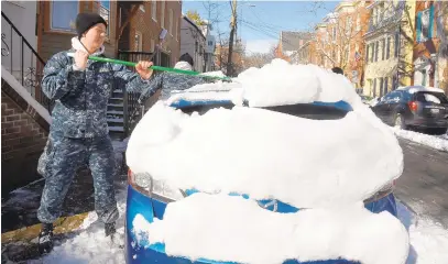  ?? PHOTOS BY PAUL W. GILLESPIE/CAPITAL GAZETTE ?? Midshipmen 1st Class Josh Hemsworth, from 14th Company, removes snow from a car on Prince George Street. Midshipmen from the Naval Academy help their neighbors around the outside of the yard by shoveling snow off streets and cars.