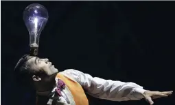  ?? - Associated Press: Rick Rycroft ?? Un artiste tient en équilibre une ampoule sur sa tête lors d’une démonstrat­ion de la production du Cirque du Soleil Kurios: Cabinet des curiosités, à Sydney.