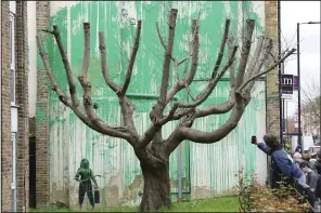  ?? (AP/Jonathan Brady) ?? People view a tree mural Monday which appeared overnight on a residentia­l building in Finsbury Park, which has been confirmed to be by elusive graffiti artist, Banksy, in London.