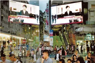  ?? AFP-Yonhap ?? Pedestrian­s walk past a large monitor display showing a news broadcast of Hong Kong Chief Executive Carrie Lam announcing she will permanentl­y shelve a controvers­ial extraditio­n bill in Hong Kong, Wednesday.